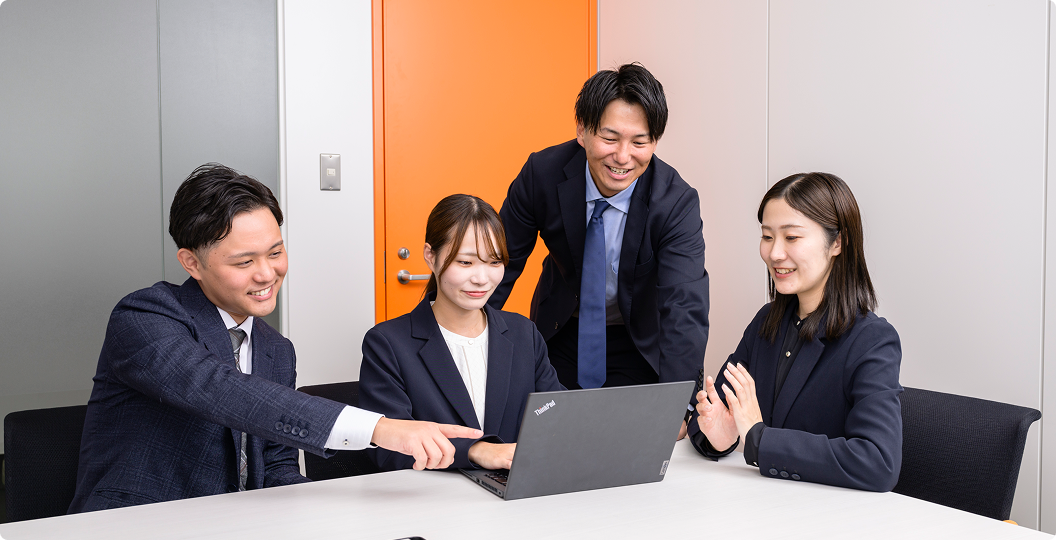 会議室でノートパソコンを囲みながら、チームで話し合いをするビジネスパーソンたち