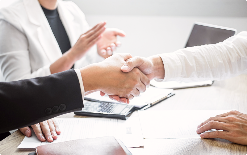 ビジネスの場でスーツ姿の人物同士が握手を交わしている様子