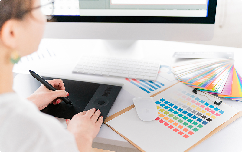 デジタルペンを使って液晶ペンタブレットで作業するデザイナーの手元